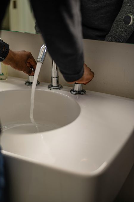 a man turns the water on at a bathroom sink
