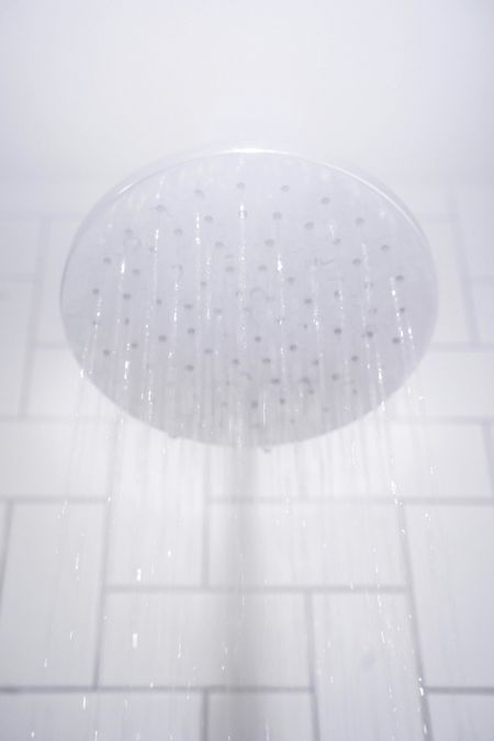 hot water steaming from a shower head in a home with a well maintained hot water heater